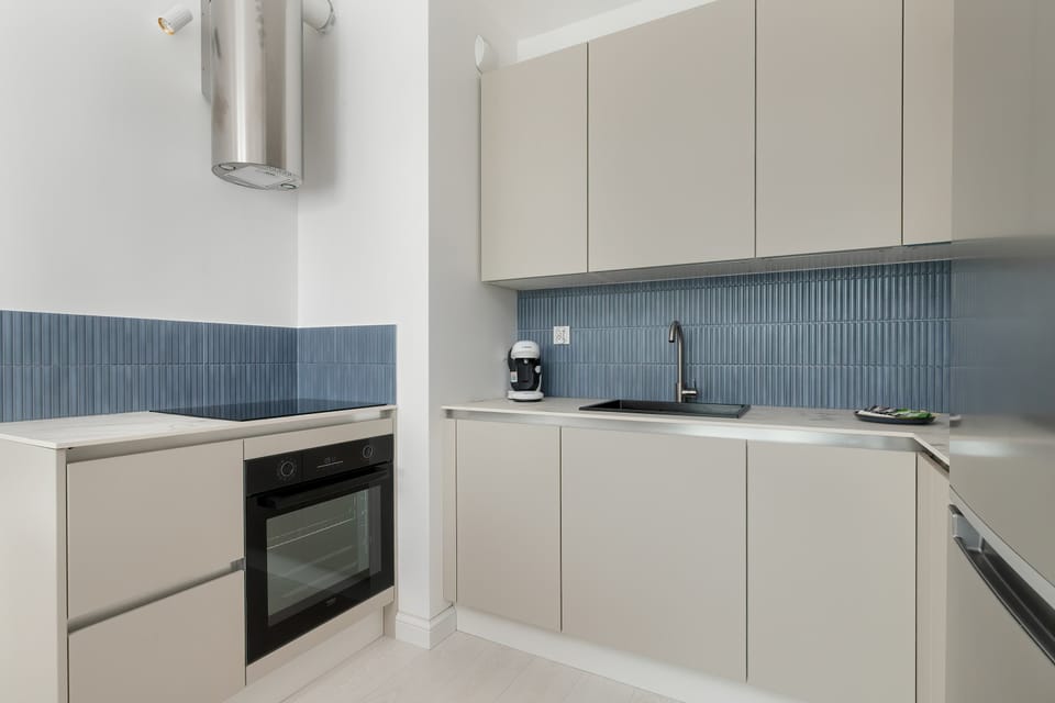 A modern kitchenette with white cabinets and full equipment allows for convenient meal preparation.