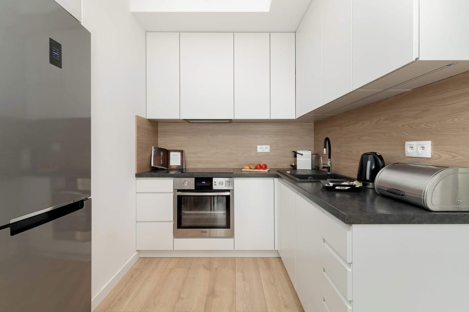 A modern L-shaped kitchen with white cabinets, wooden countertops, and black kitchen appliances.
