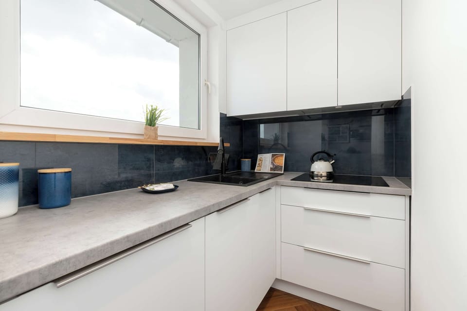 White L-shaped kitchen featuring dark countertops and overhead storage.