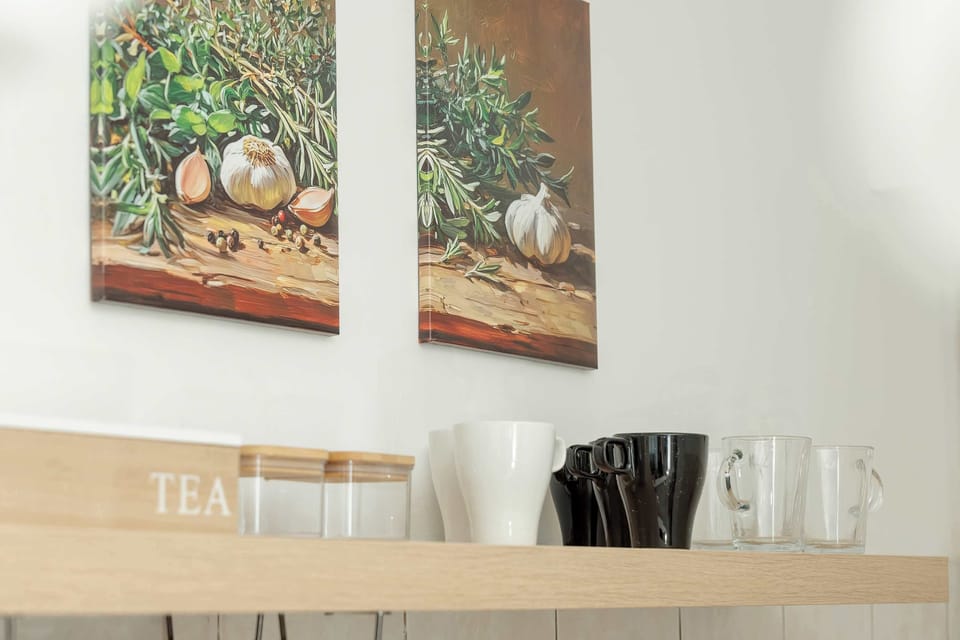 A neutral-toned wall art piece hanging above a wooden cabinet, with glasses neatly arranged.

