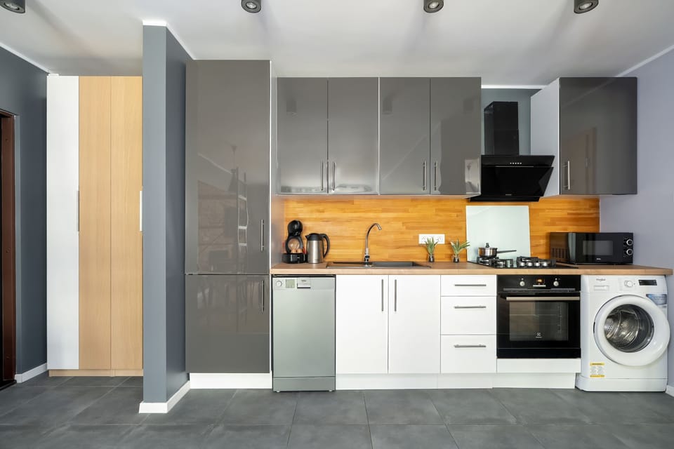 A modern compact kitchen with a white and black color scheme, wooden accents, and overhead lighting.