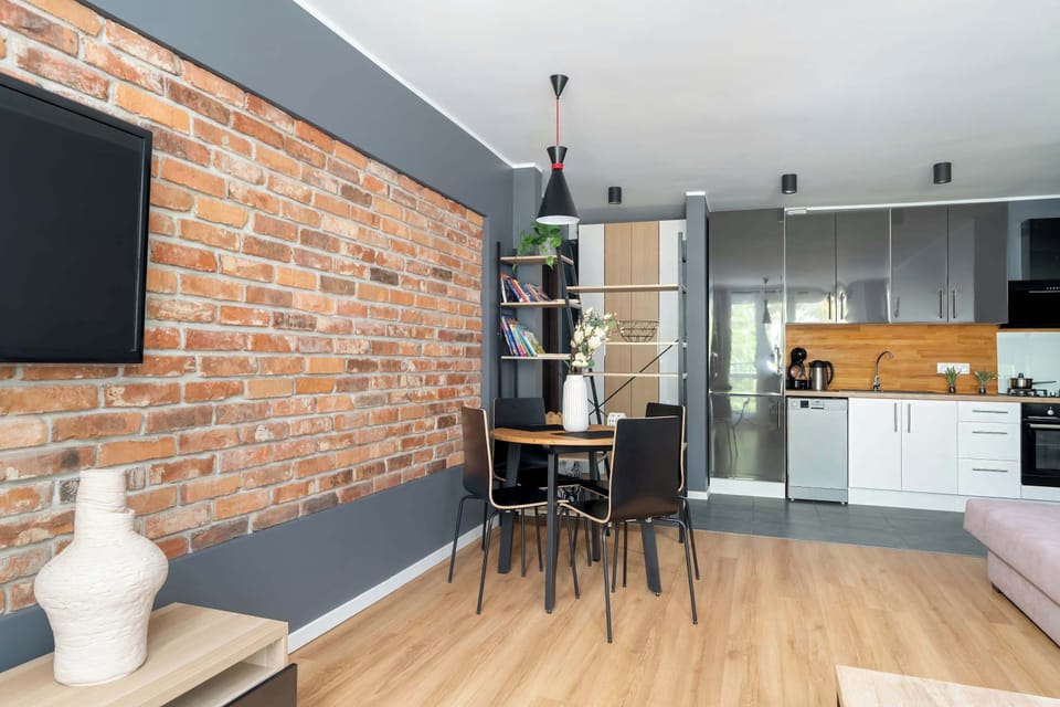 A full view of the open living and kitchen area, combining exposed brick with modern finishes and light wood floors.