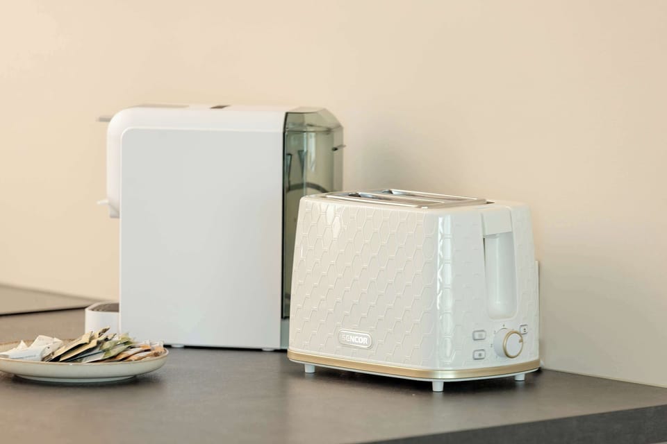 A small appliance setup including a white toaster and kettle, arranged neatly on a black counter for guests’ convenience.