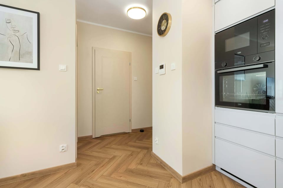A clean, neutral-toned hallway connecting different rooms, with wooden flooring and modern lighting.
