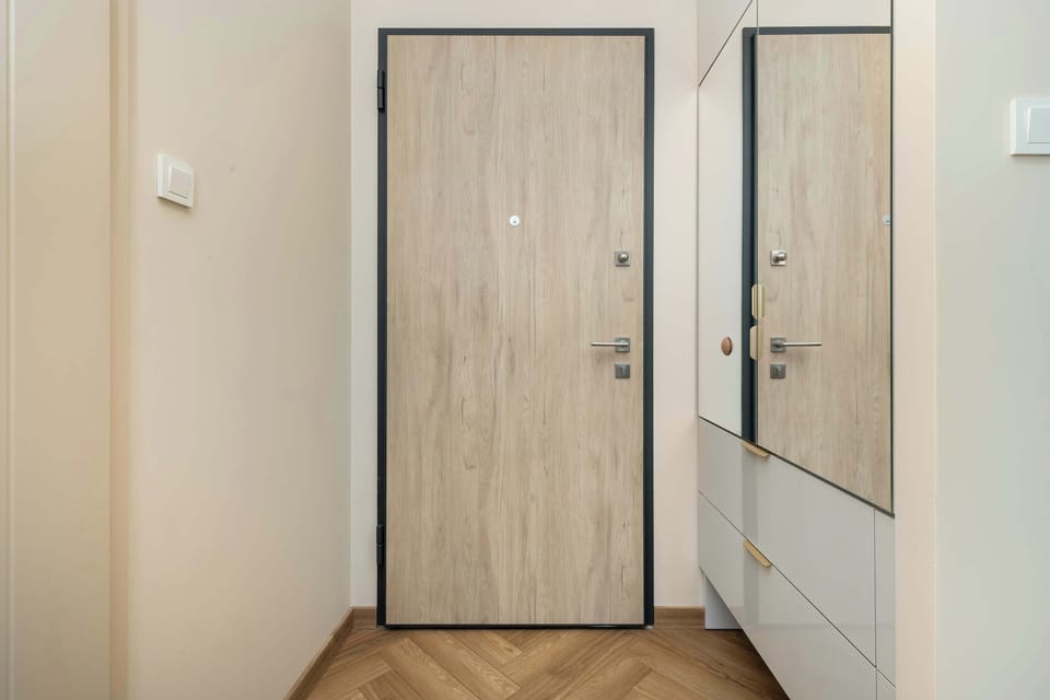 A small entry hallway with wooden flooring and a neutral palette, featuring a built-in closet with mirrored doors.