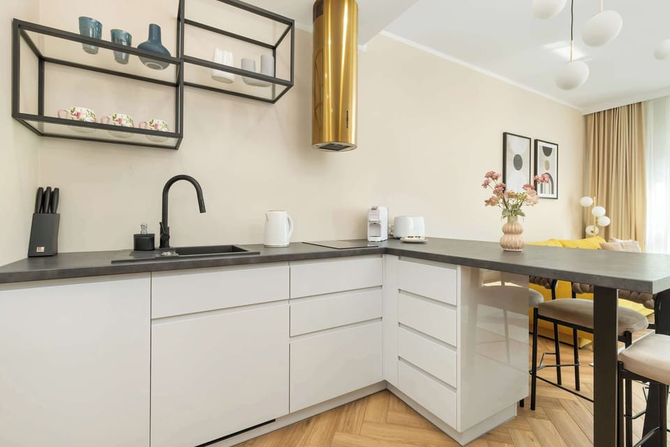 A modern kitchen with matte cabinetry, golden accents, and integrated appliances for stylish home cooking.