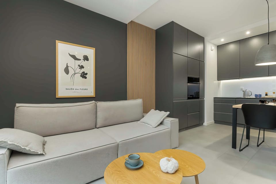 The stylish living room is coherently connected by a dining table and a modern kitchenette.