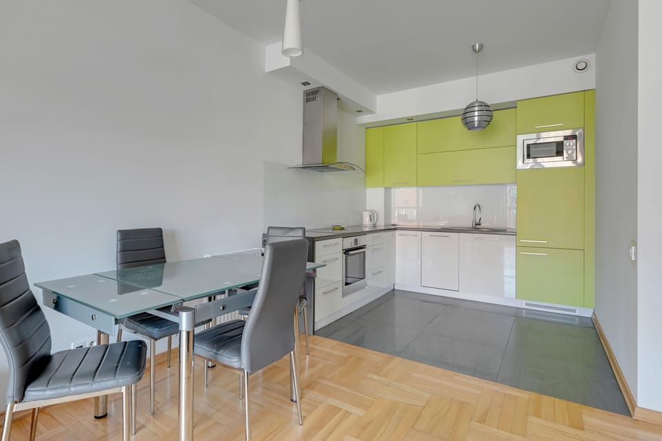 A contemporary kitchen designed with light wooden countertops, white cabinetry, and modern stainless steel appliances, offering both functionality and style.