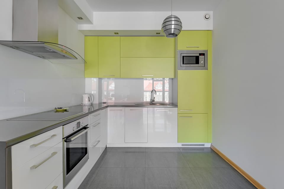 A funkcional kitchen designed with light wooden countertops, white cabinetry, and modern stainless steel appliances, offering both functionality and style.
