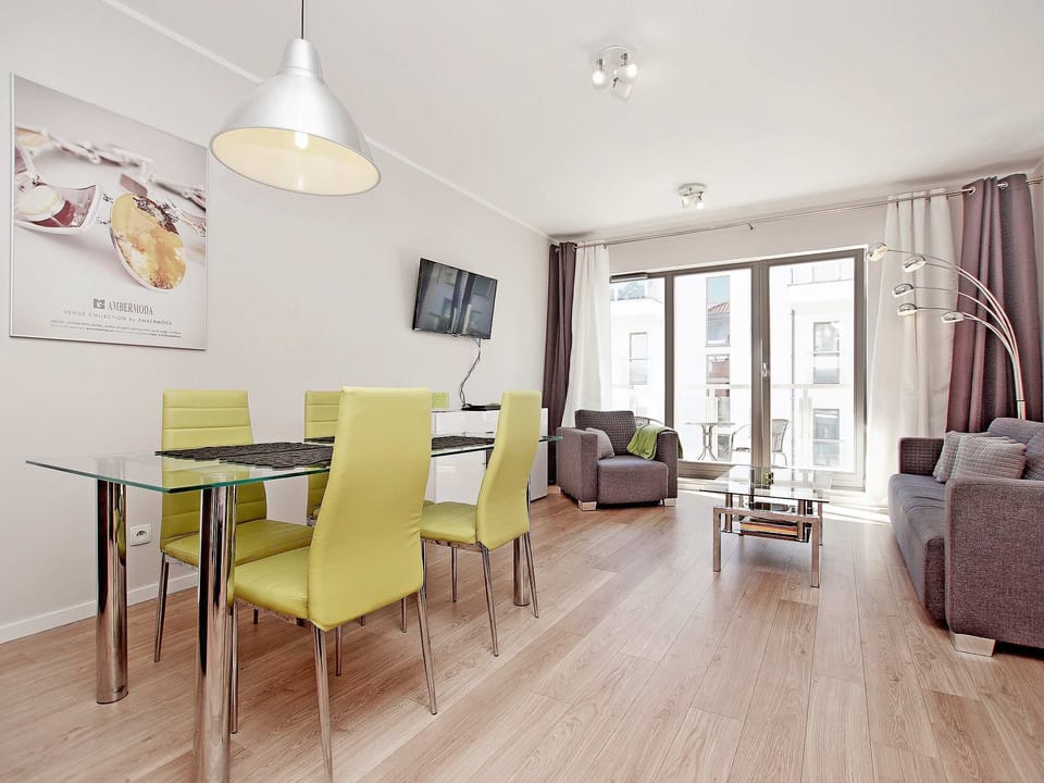 Bright living room with a sofa bed, TV, dining area and access to balcony.