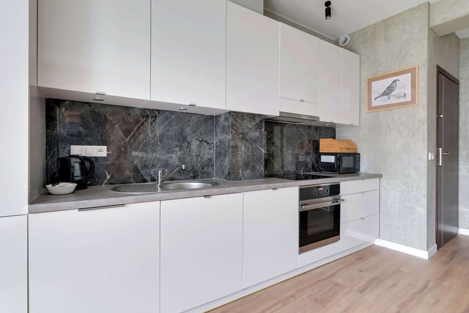 A white minimalist kitchen with a grey countertop and built-in appliances.