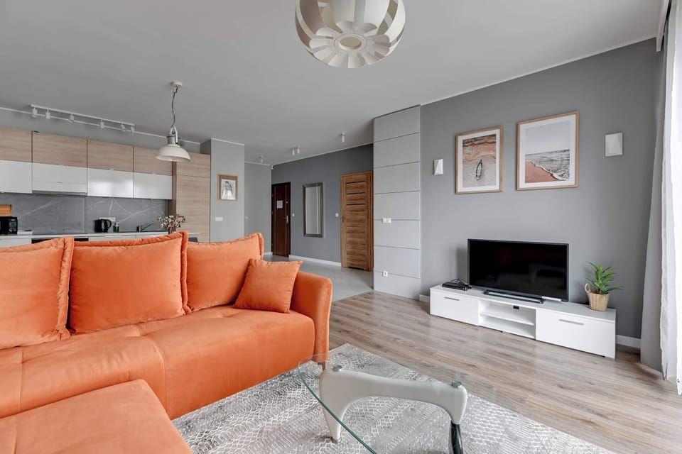 A vibrant living area featuring an orange sectional sofa, a stylish wall mural, and modern decor.