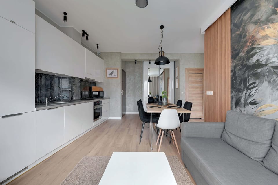 An open-concept kitchen and living area with modern furnishings and a combination of white and wooden elements. The space feels bright and welcoming.