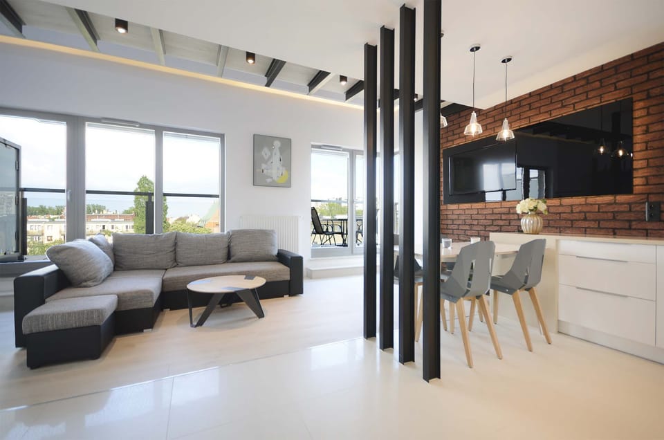 Spacious living room with a corner sofa bed, TV, dining area and access to the balcony.