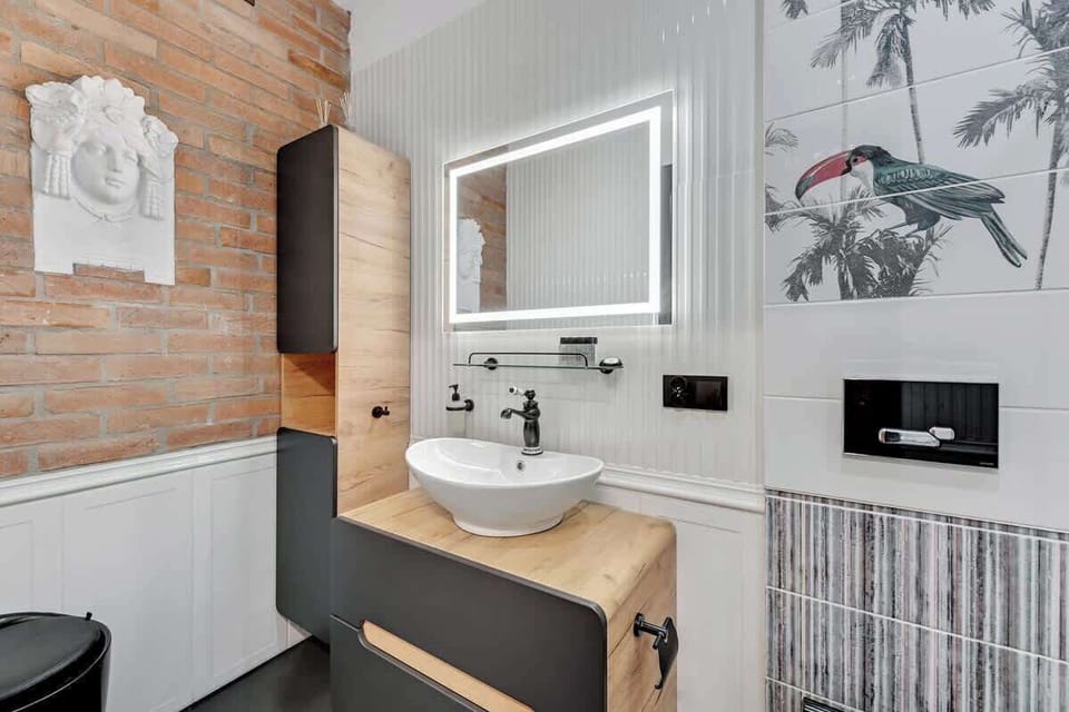 The modern and elegant bathroom impresses with its minimalist design. A spacious shower cabin with a rain showerhead offers a relaxing experience, while light tiles paired with black accents add a striking touch.