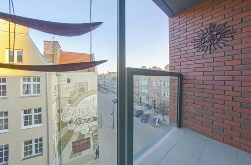 The balcony is equipped with a table, chairs, lighting, privacy screens, and a view of the surroundings.