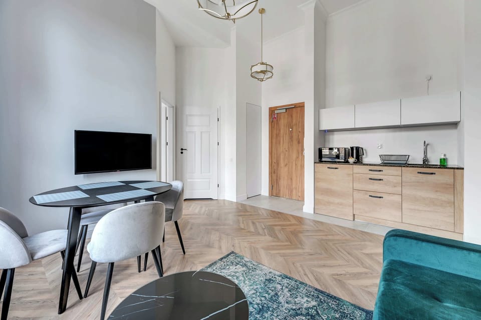 An open-plan layout combining a modern living room with a gray sofa, and a dining area that connects to the kitchen.