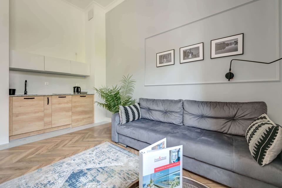 An open-plan layout combining a modern living room with a gray sofa, and a dining area that connects to the kitchen.