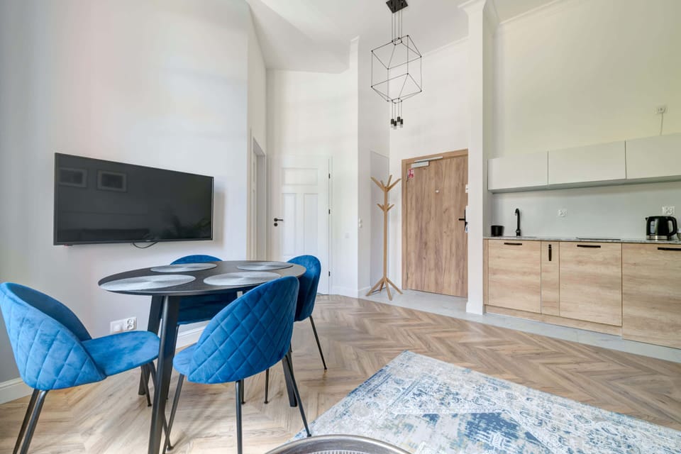 Another angle of the living area with a round dining table, blue chairs, and a well-lit, inviting atmosphere.