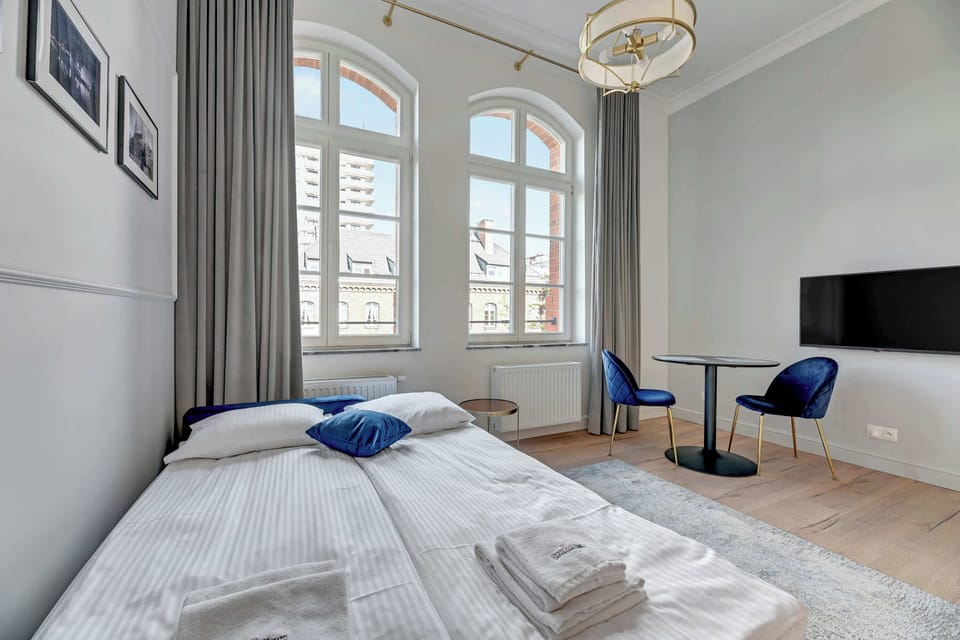 Another angle of the studio showcasing the arched windows, a compact dining table with blue chairs, and a comfortable atmosphere.