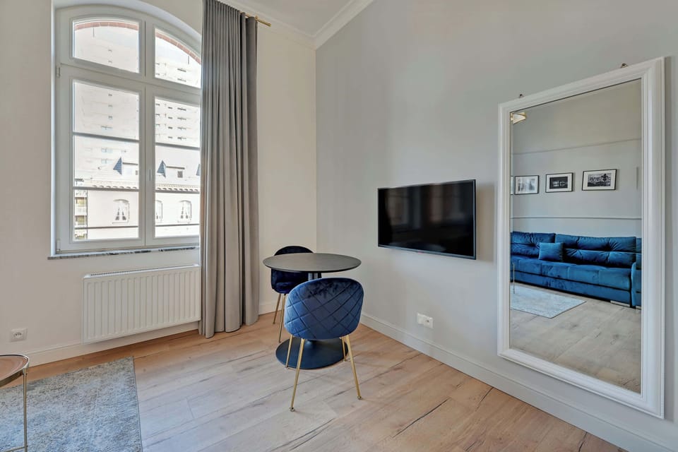 A bright and cozy studio with a blue sofa, arched windows, and framed artwork adding a decorative touch.