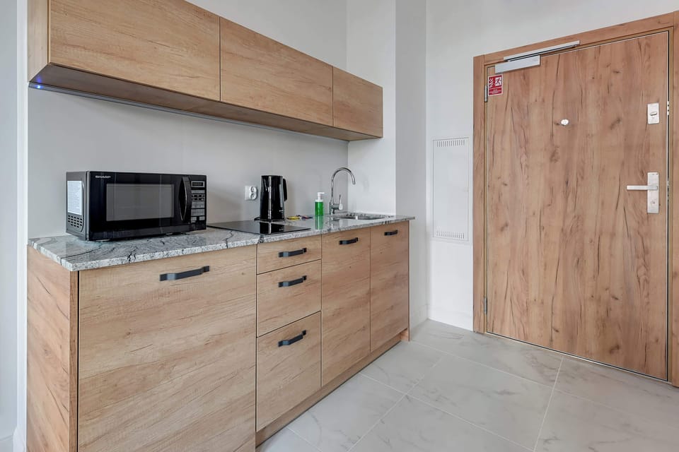 A modern kitchenette with wooden cabinetry, integrated appliances, and a simple, functional layout.