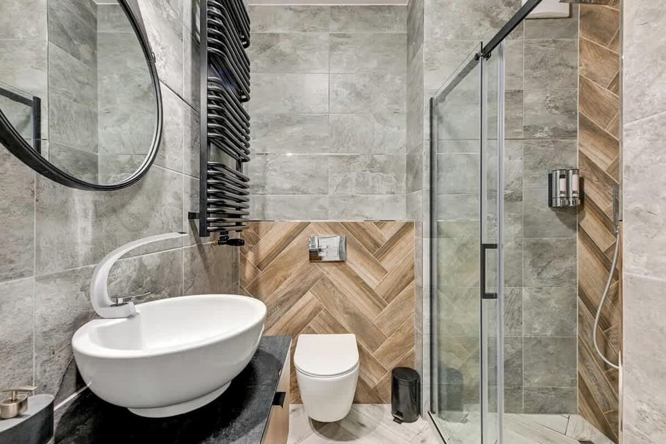 Minimalist style, with elegant grey and wood accents, a chic oval sink, and a glass shower that seamlessly blends functionality and luxury.