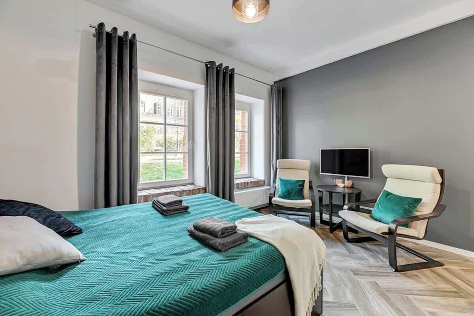 Stylish fusion of deep greys and vibrant teal, complemented by modern furniture, sleek lighting, and large windows that bathe the space in natural light