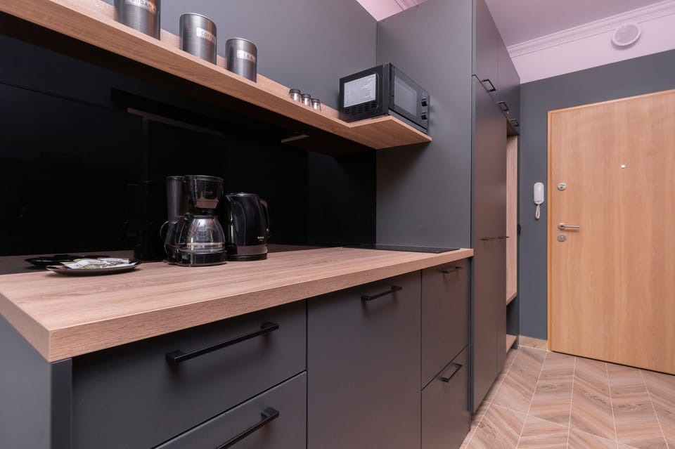  Modern kitchen with black cabinets and wooden countertops, offering ample storage and workspace.