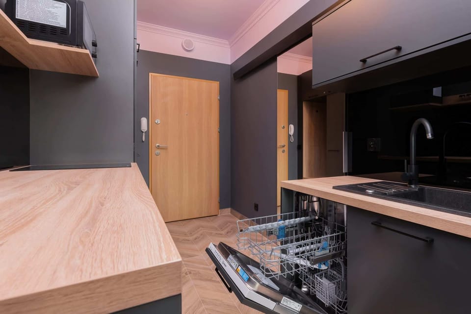 A sleek kitchen with black cabinets, wooden countertops, and modern appliances, offering a functional cooking space.