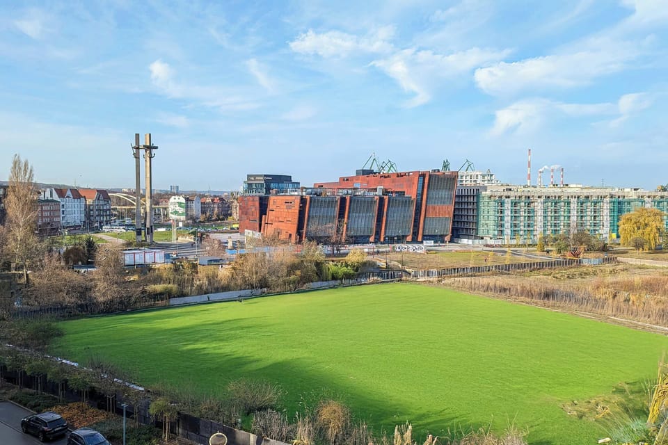 A wide view of the neighborhood, showcasing green fields and a mix of urban architecture.