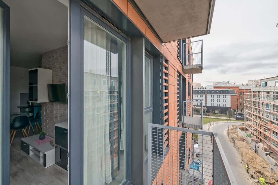  The modern architecture of the buildings and the greenery in the surroundings. The balcony offers a spacious area for relaxation, where guests can enjoy fresh air and a view of the city.