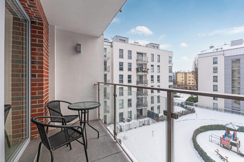 The third picture depicts a balcony with a small table and two chairs, offering a view of an open courtyard surrounded by white residential buildings. The space looks bright and welcoming, ideal for enjoying fresh air.
