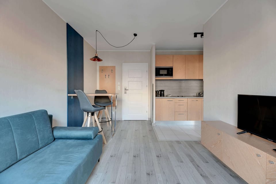 The living area is extended to show the TV cabinet and additional seating options. The design emphasizes functionality while maintaining a modern aesthetic.