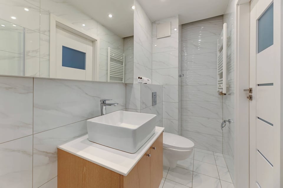 Bathroom with a modern sink, a large mirror, and a floating vanity. The light marble tones of the walls and floor create a clean and elegant look.