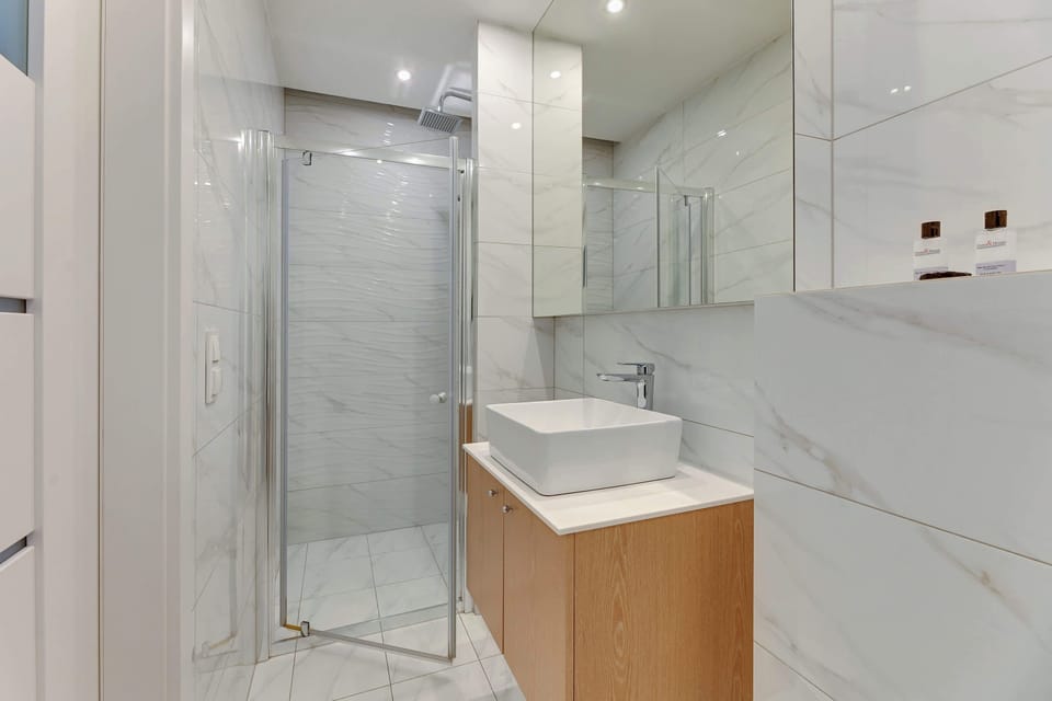 Bathroom with a modern sink, a large mirror, and a floating vanity. The light marble tones of the walls and floor create a clean and elegant look.