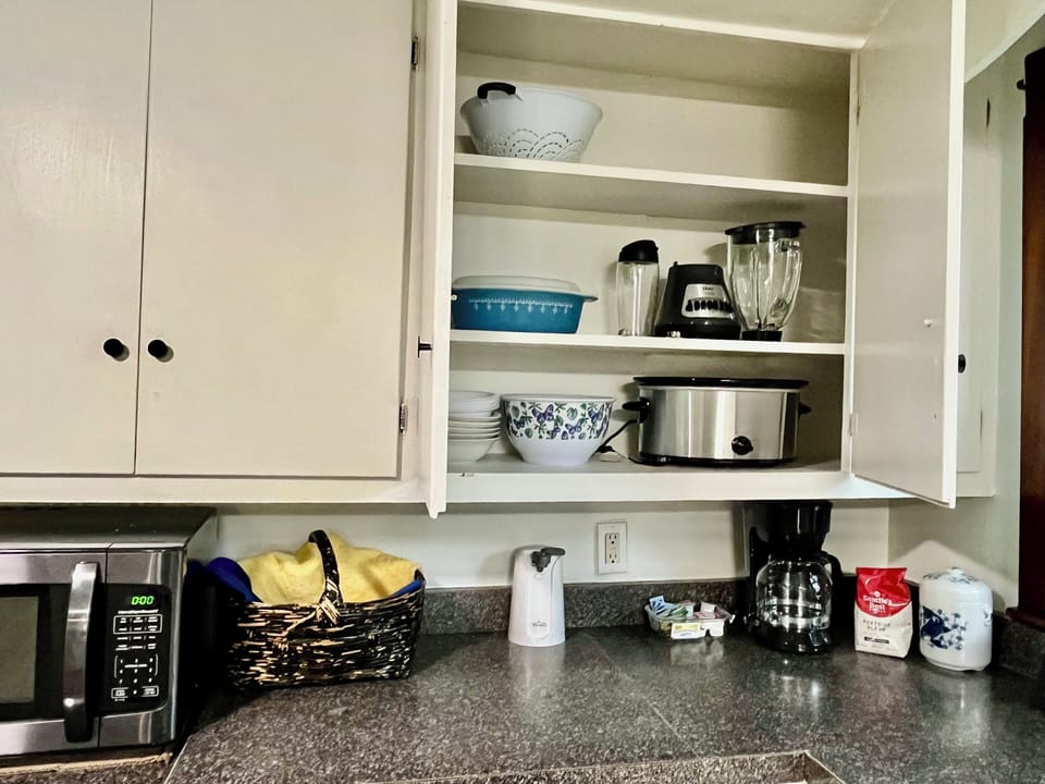 Fully stocked kitchen with appliances, pots and pans and dishes/basket of snacks