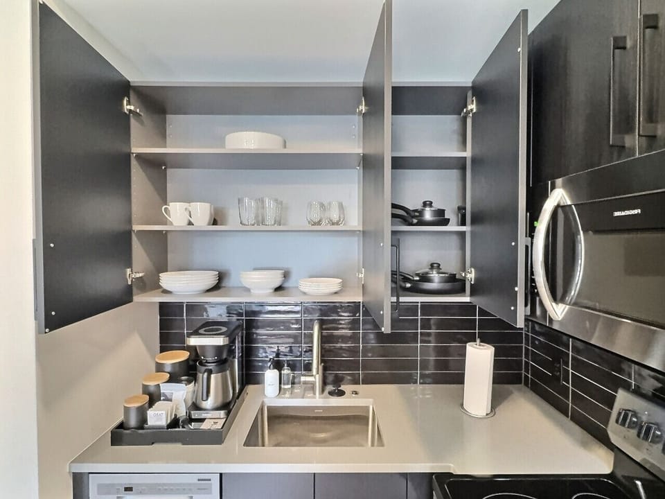 Modern kitchen with sleek stainless steel appliances and neatly arranged utensils, perfect for effortless cooking during your short-term rental stay.