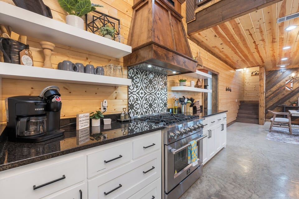 Stylish and fully stocked—this beautiful kitchen setup features open shelving, a bold backsplash, and everything you need to brew, bake, and gather in style.