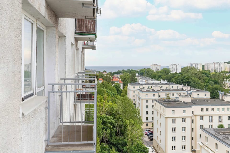 A view from a balcony overlooking a cluster of low-rise apartment buildings surrounded by trees.