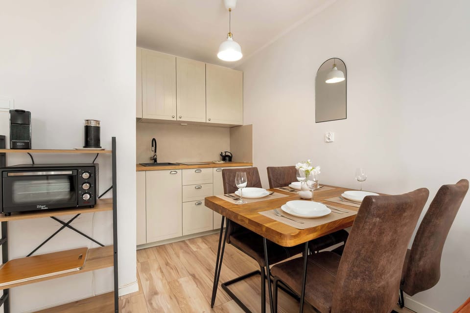 A compact dining space with a table set for four, adjacent to a small but functional kitchenette.