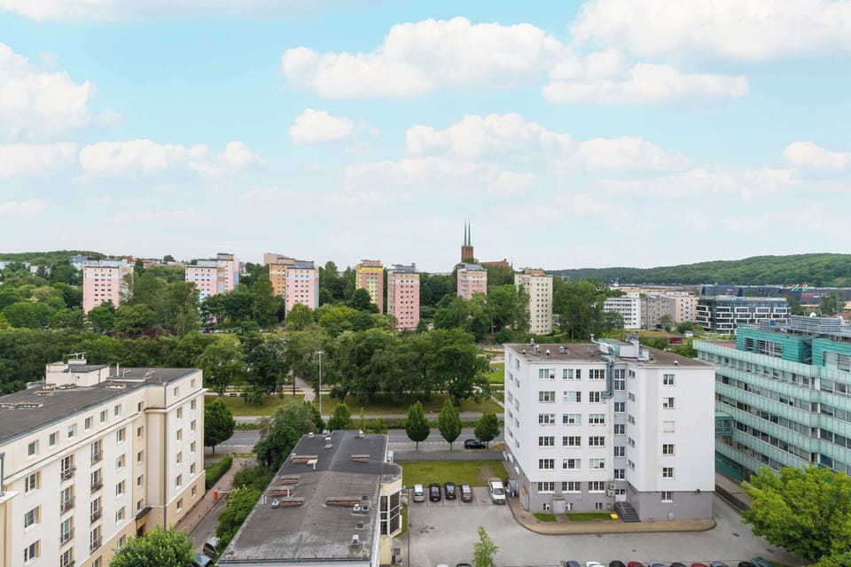 A view from a balcony overlooking a cluster of low-rise apartment buildings surrounded by trees.