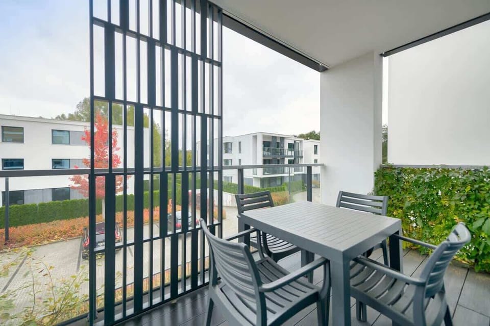 A balcony with seating, perfect for enjoying morning coffee with a view of greenery.