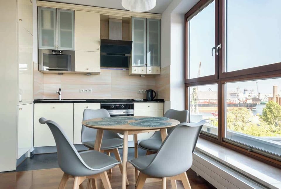 A sophisticated combination of the kitchen and dining space, bathed in natural light from expansive windows.