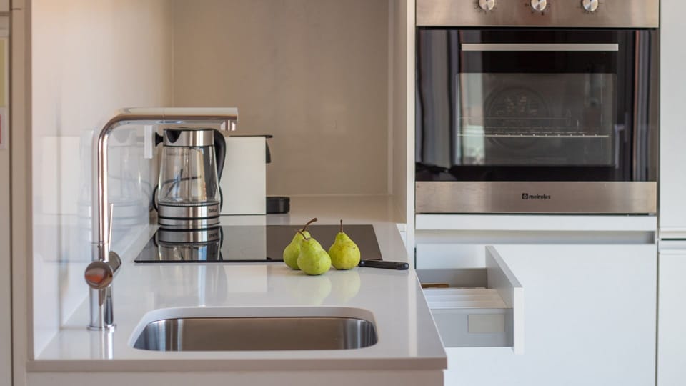 Sleek white kitchen with modern appliances — cook with style after a day by the sea. #PortoKitchen #DesignDetails