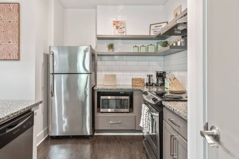 Fully stocked kitchen with stainless steel appliances, open shelving, and modern finishes