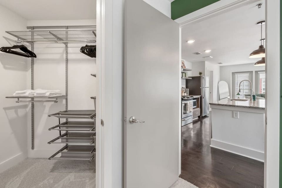 Walk-in closet with custom wire organizers and easy access to the kitchen and living area.