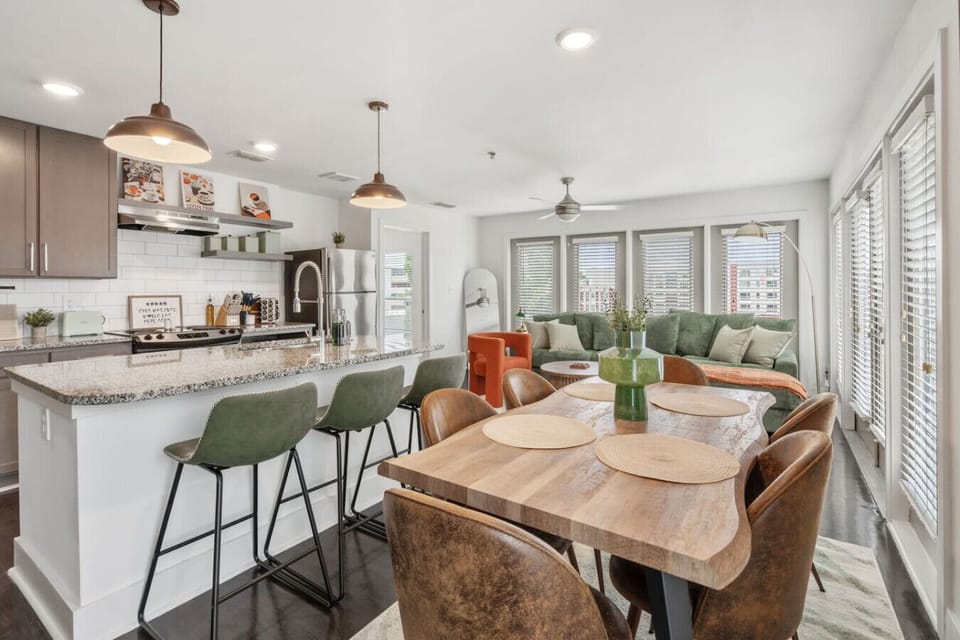 Bright, social layout with oversized island, bar seating, and dining area framed by windows.