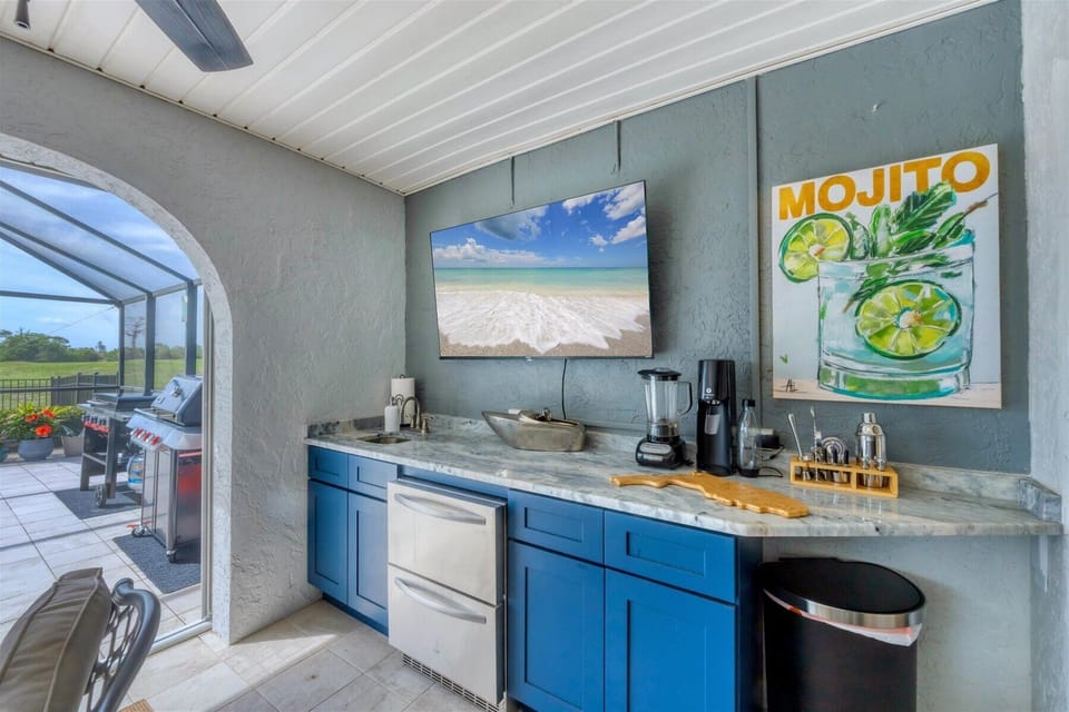 Wet bar with sink, TV, blender, and fridge—just steps from the grill & griddle.