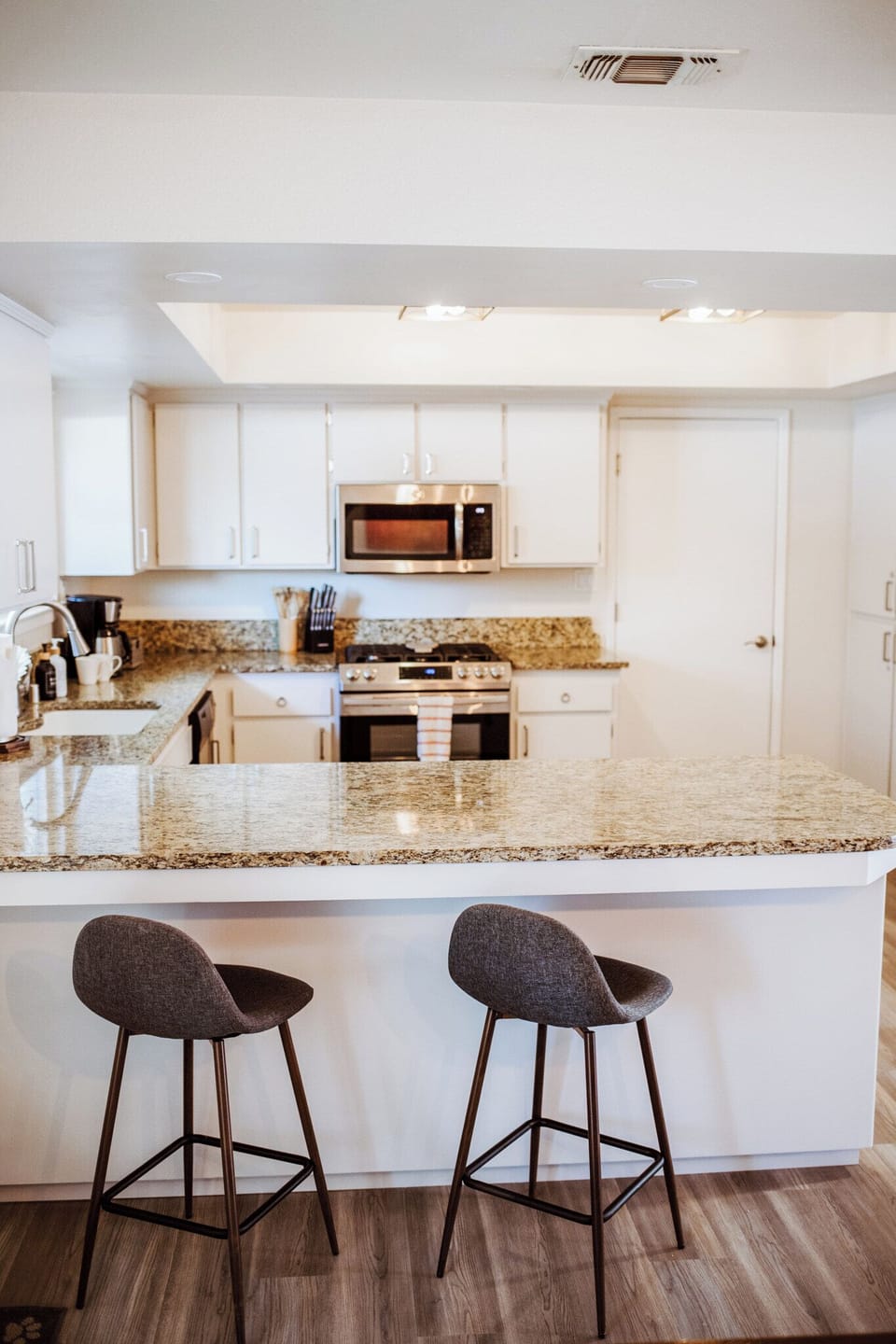 Enjoy a morning espresso at the sleek granite breakfast bar in this bright, modern kitchen.